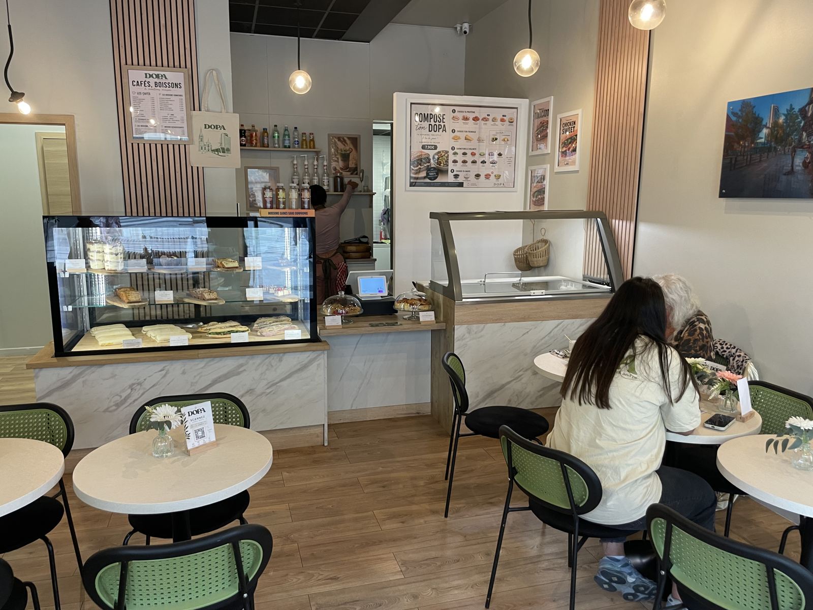 La salle de DOPA : comptoir, vitrine de pâtisseries et chaises vertes